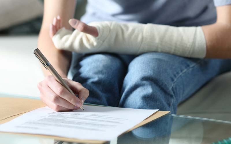 person with arm in cast signing paper